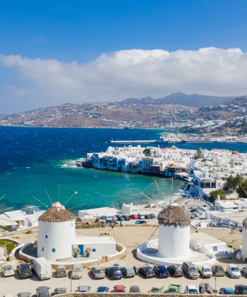 Greek island coastal town with whitewashed buildings, windmills and turquoise sea