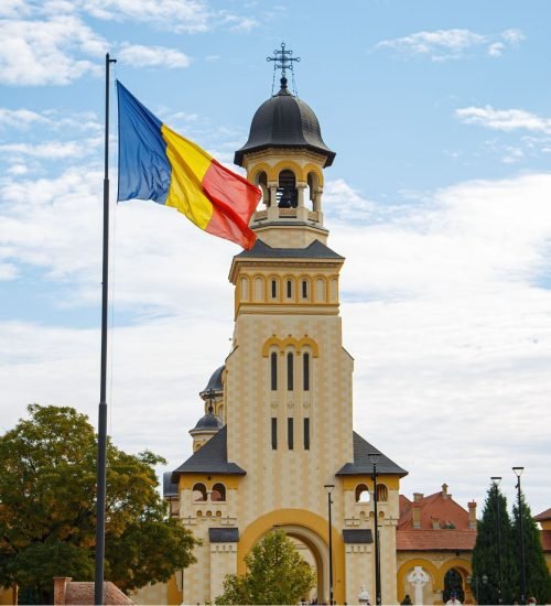 Historic Romanian church with a Romanian flag in front