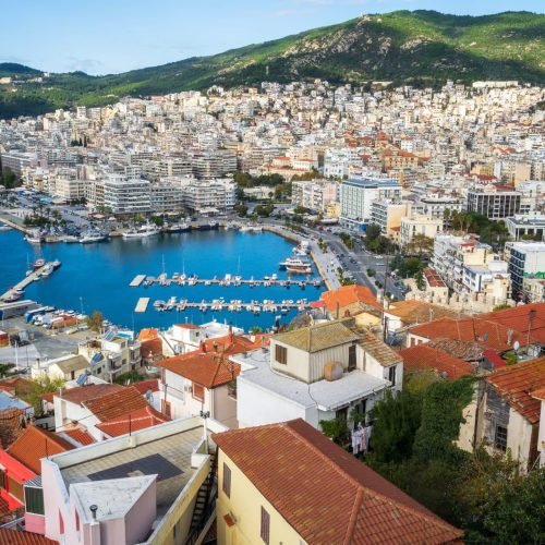 Coastal city in Northern Greece overlooking a blue harbor and surrounding hills